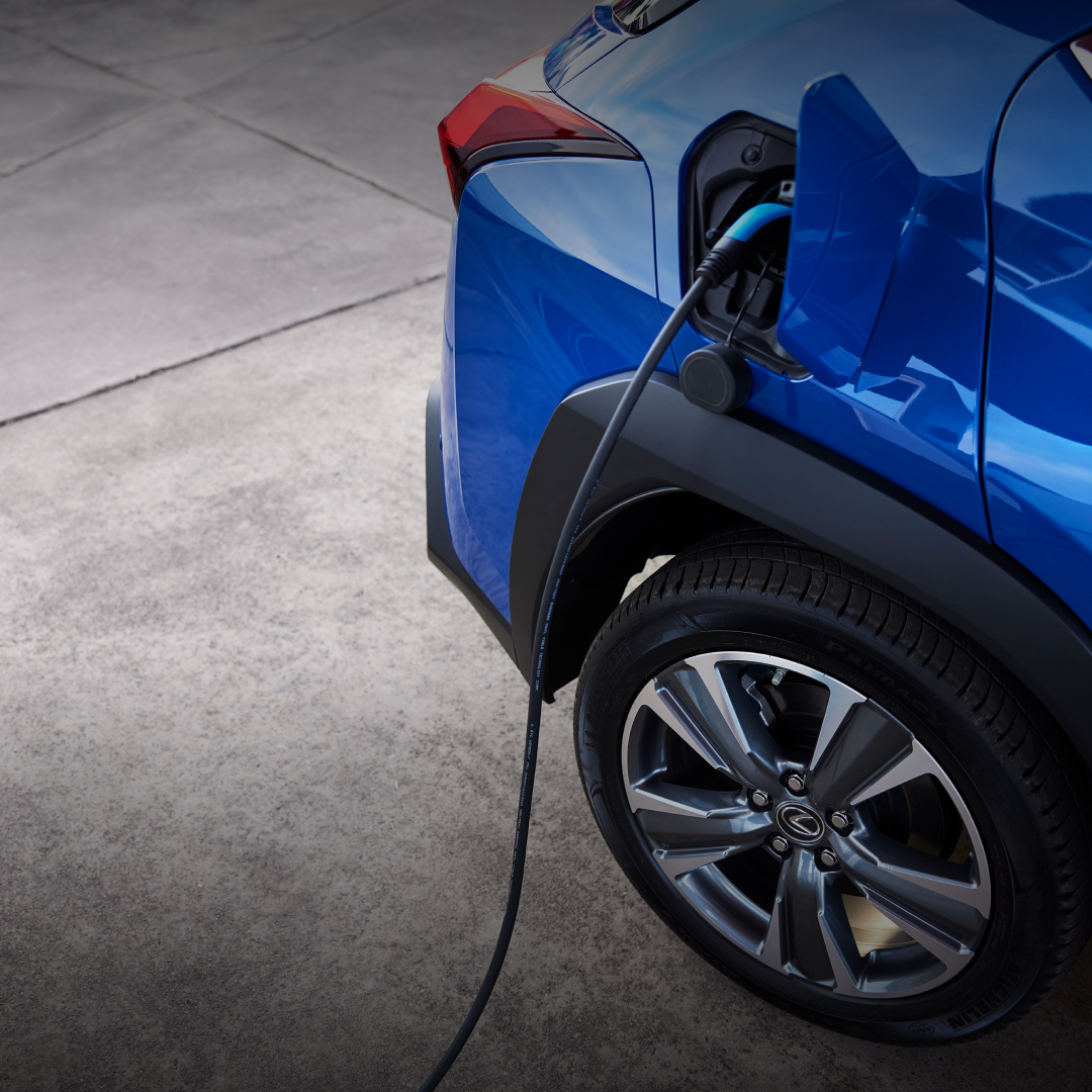 A blue UX 300e sits charging on grey pavement