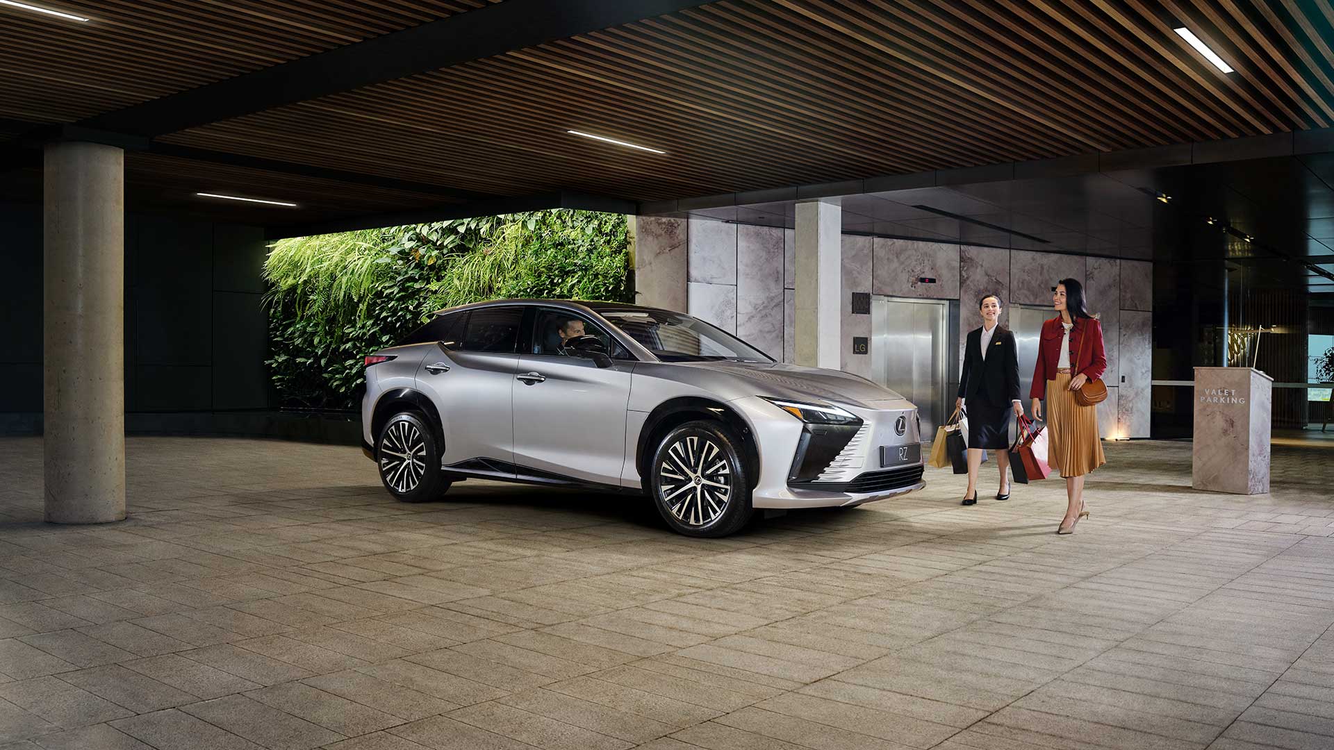 A well dressed lady collects her Lexus RZ from a valet parking service
