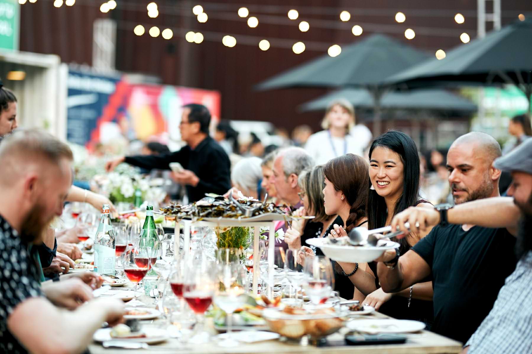People dining and enjoying wine at a lively outdoor event during the Melbourne Food and Wine Festival.