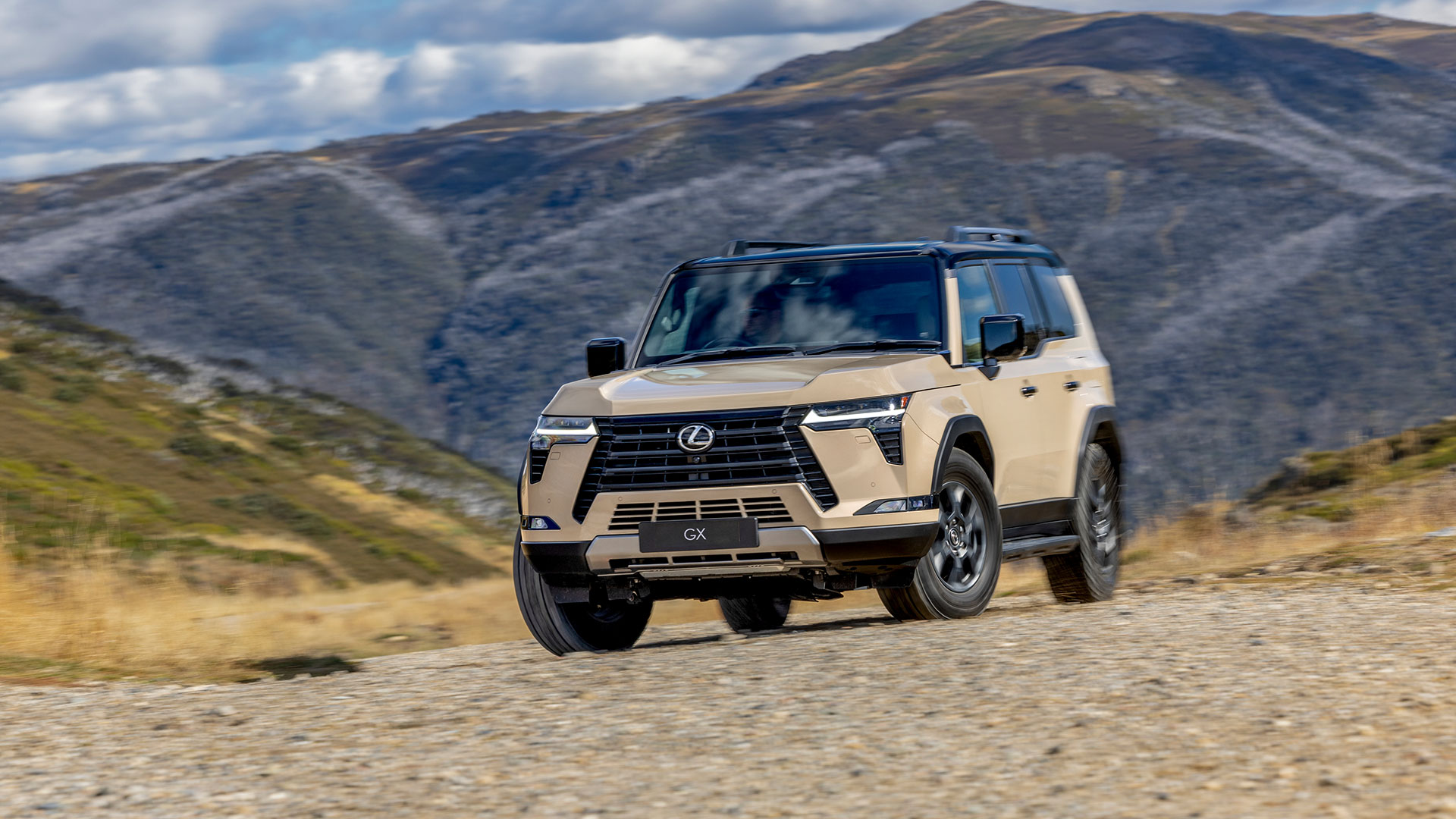 Lexus GX in Earth tone, parked against a mountainous backdrop