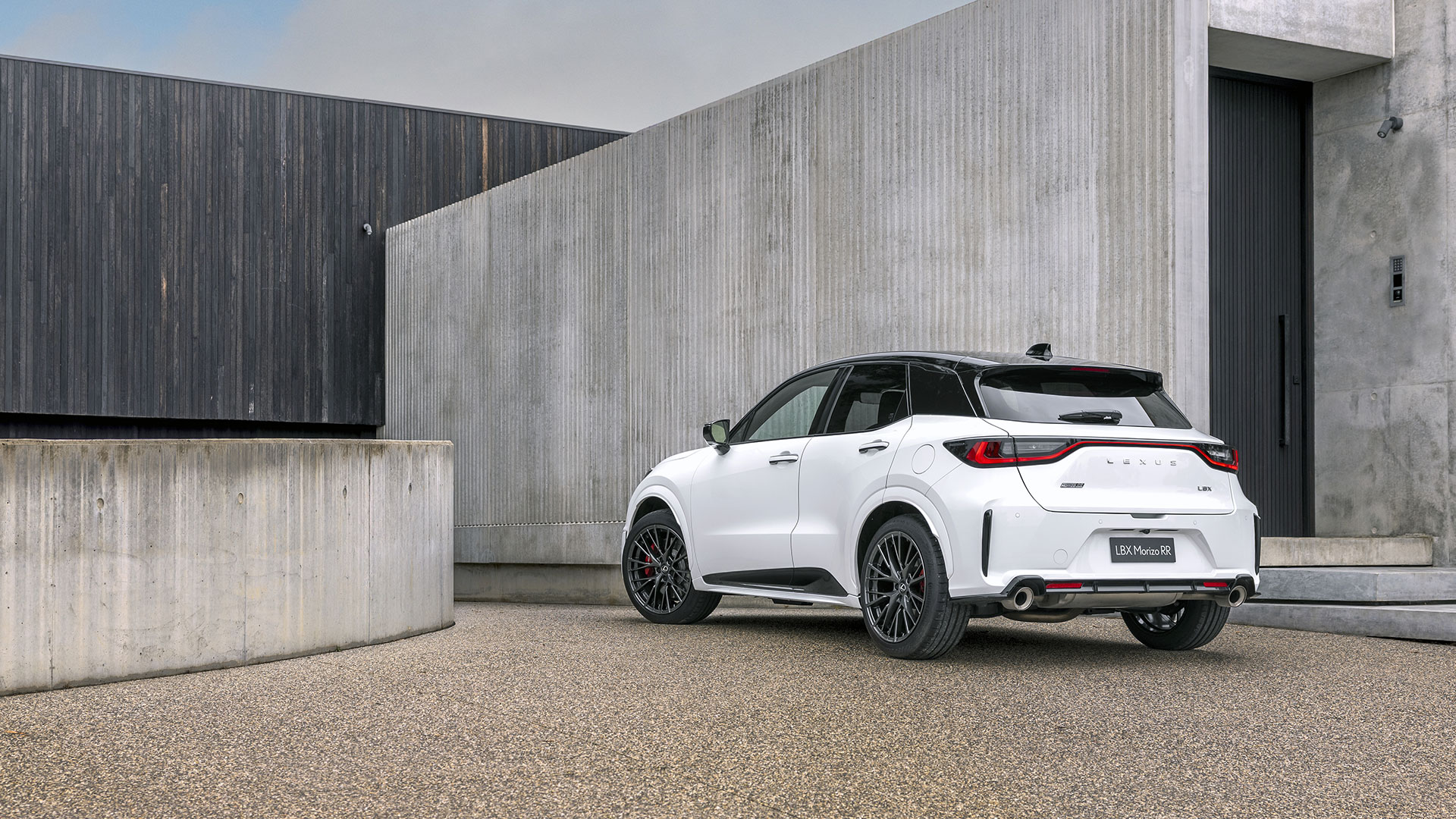 A white Lexus LBX Morizo RR parked in front of a cement building