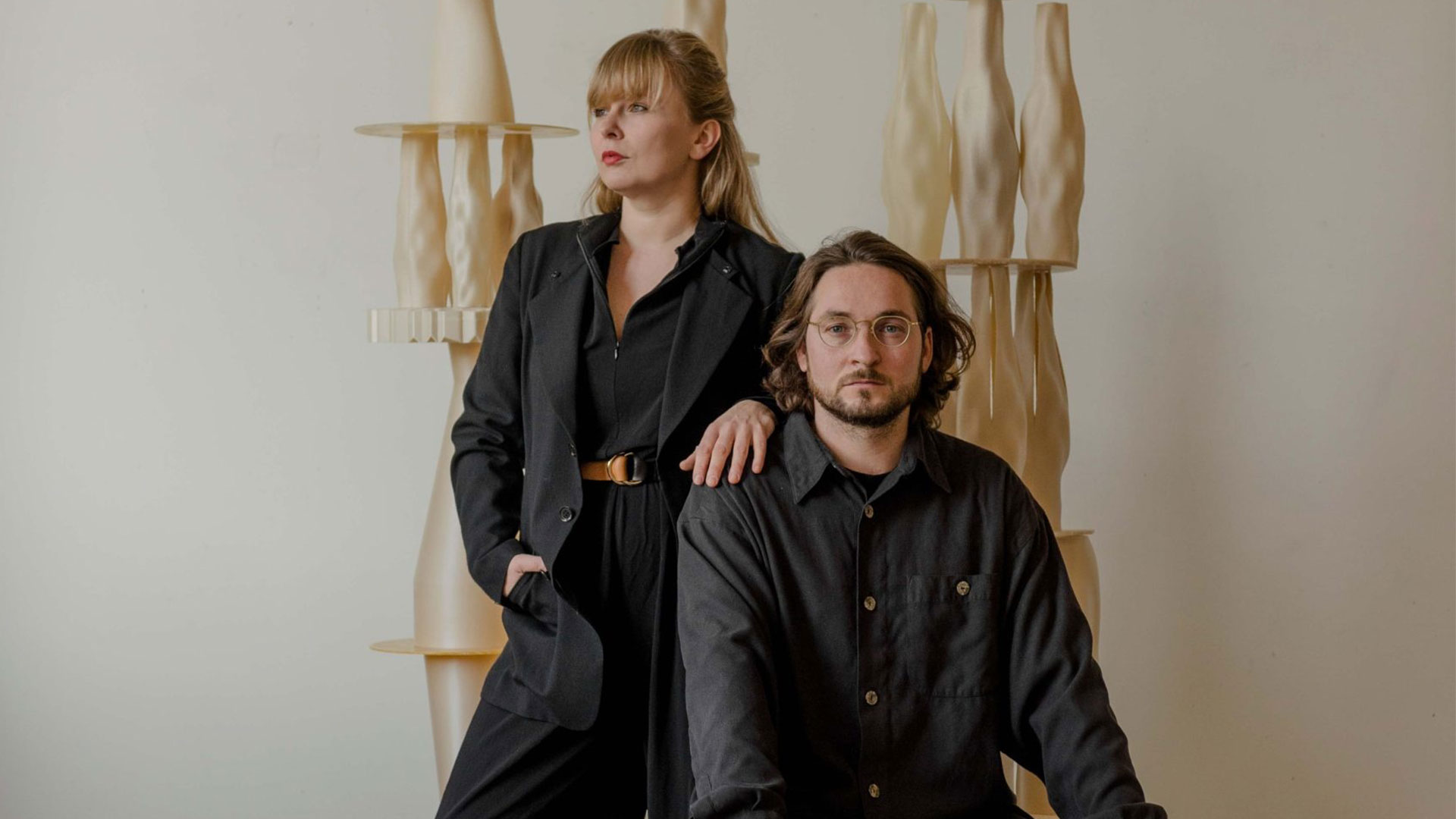 Vlasta Kubusova and Miroslav Kral posing in a studio space with sculptural forms behind them