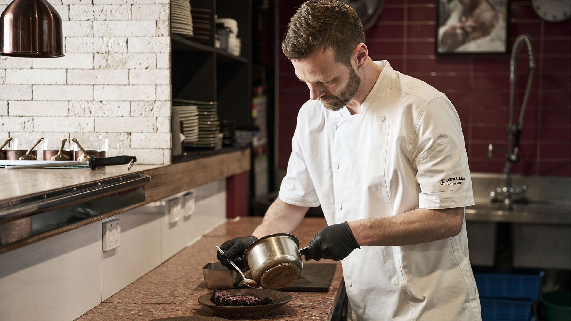 Chef Josh Raine plating a dish in a professional kitchen
