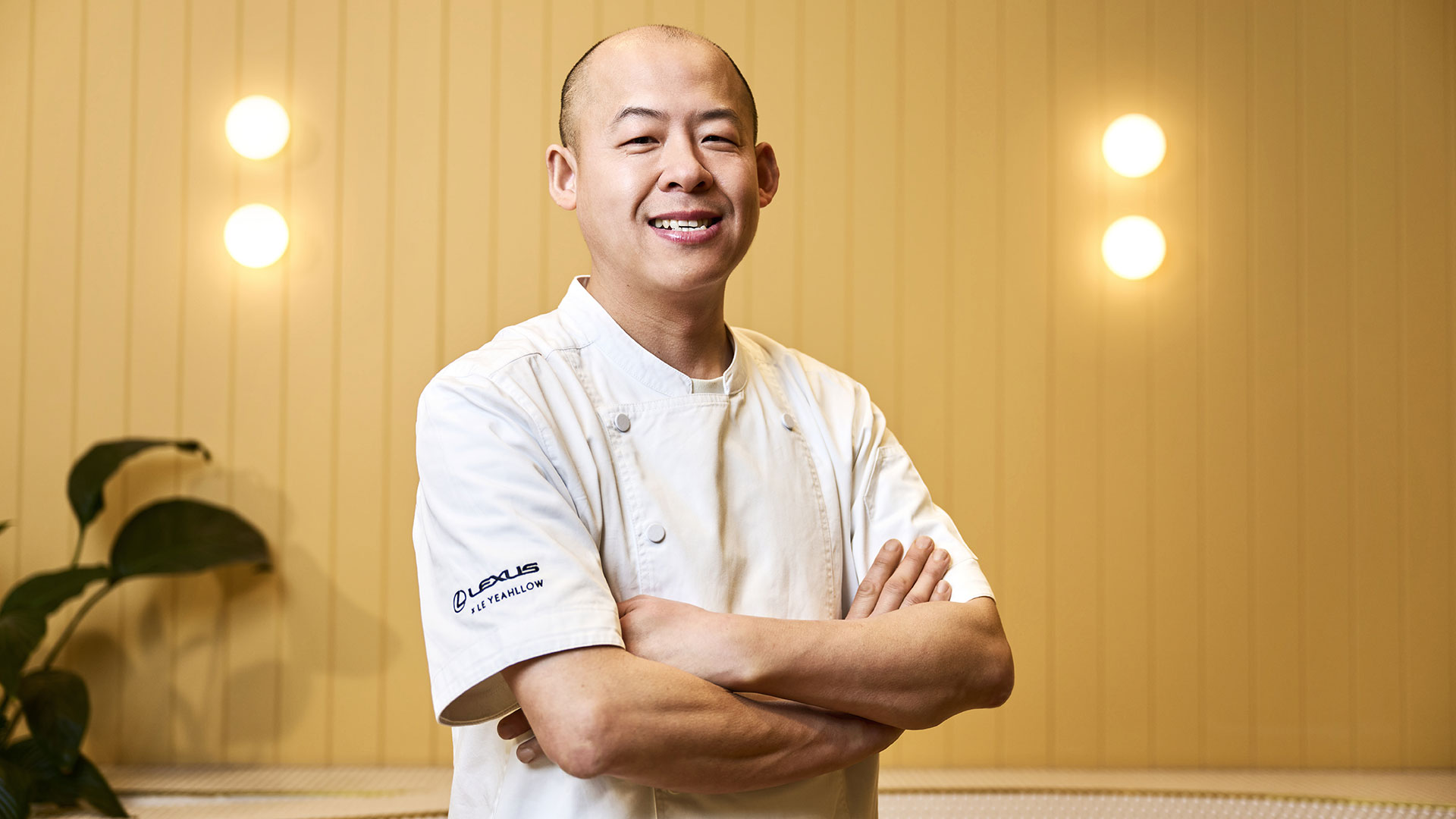 Pastry chef Steven He standing with arms crossed in a restaurant interior